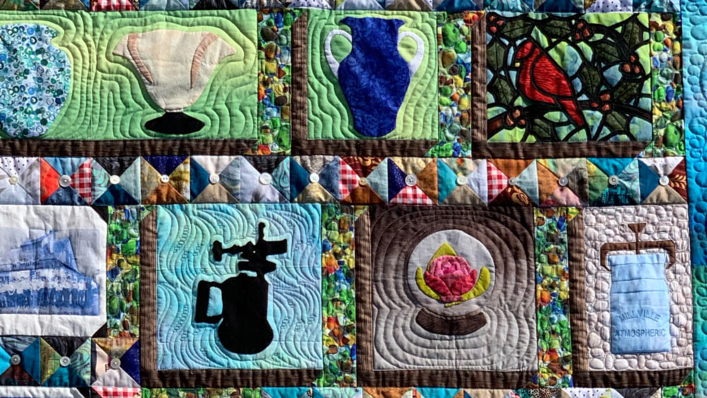 There is a close-up of a finished quilt with squares of various glass vases, paperweights, and stained glass.