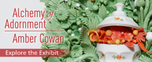 "Alchemy of Adornment: Explore the Exhibit" is displayed over a close-up of the detail on the Alchemy of Adornment exhibit artist Amber Cowan's glass sculpture is of a pot of orange flowers surrounded by pale green flowers & leaves.